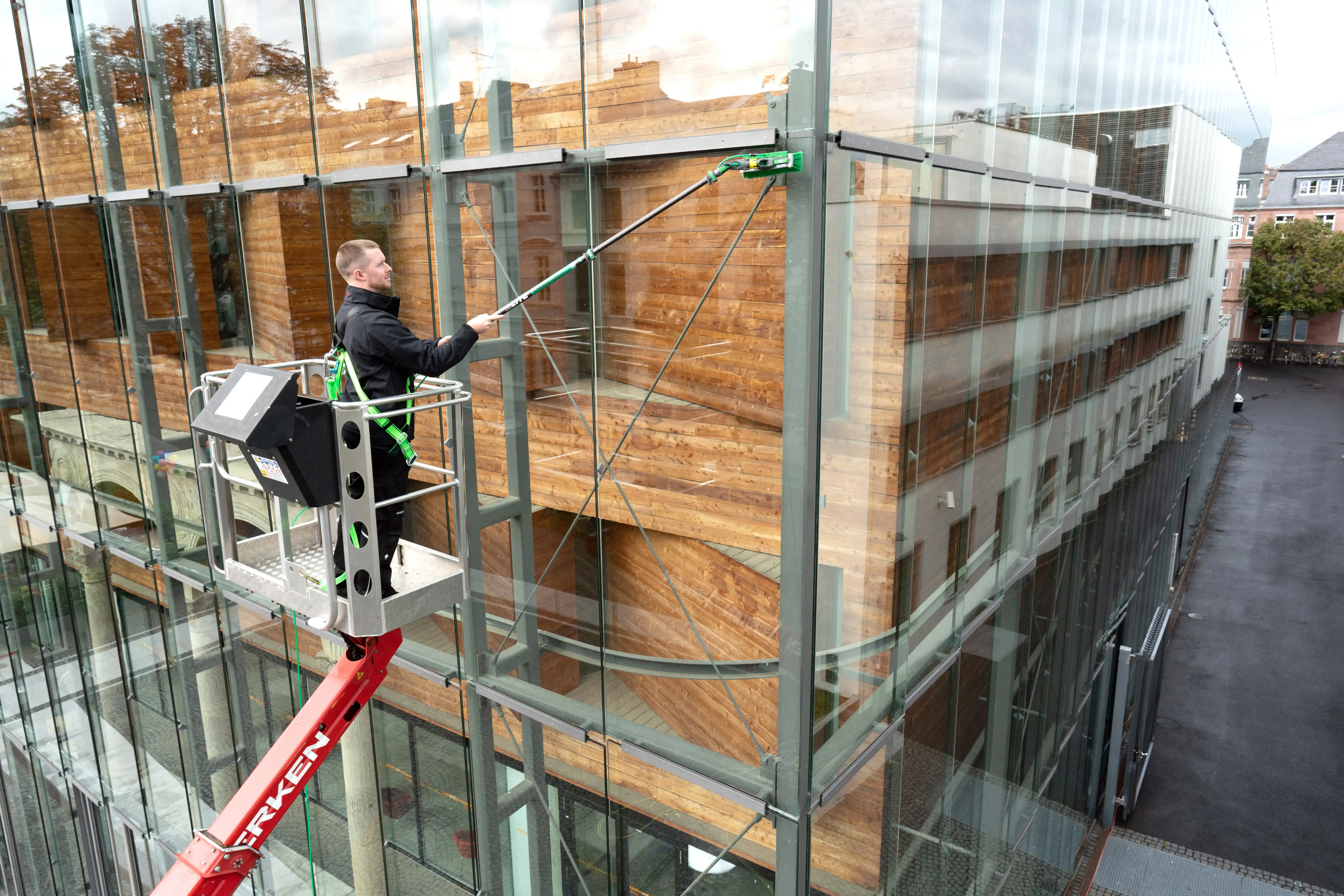 Arbeiter reinigt Glasfassade mit nLite Carbon Composite Teleskopstange.