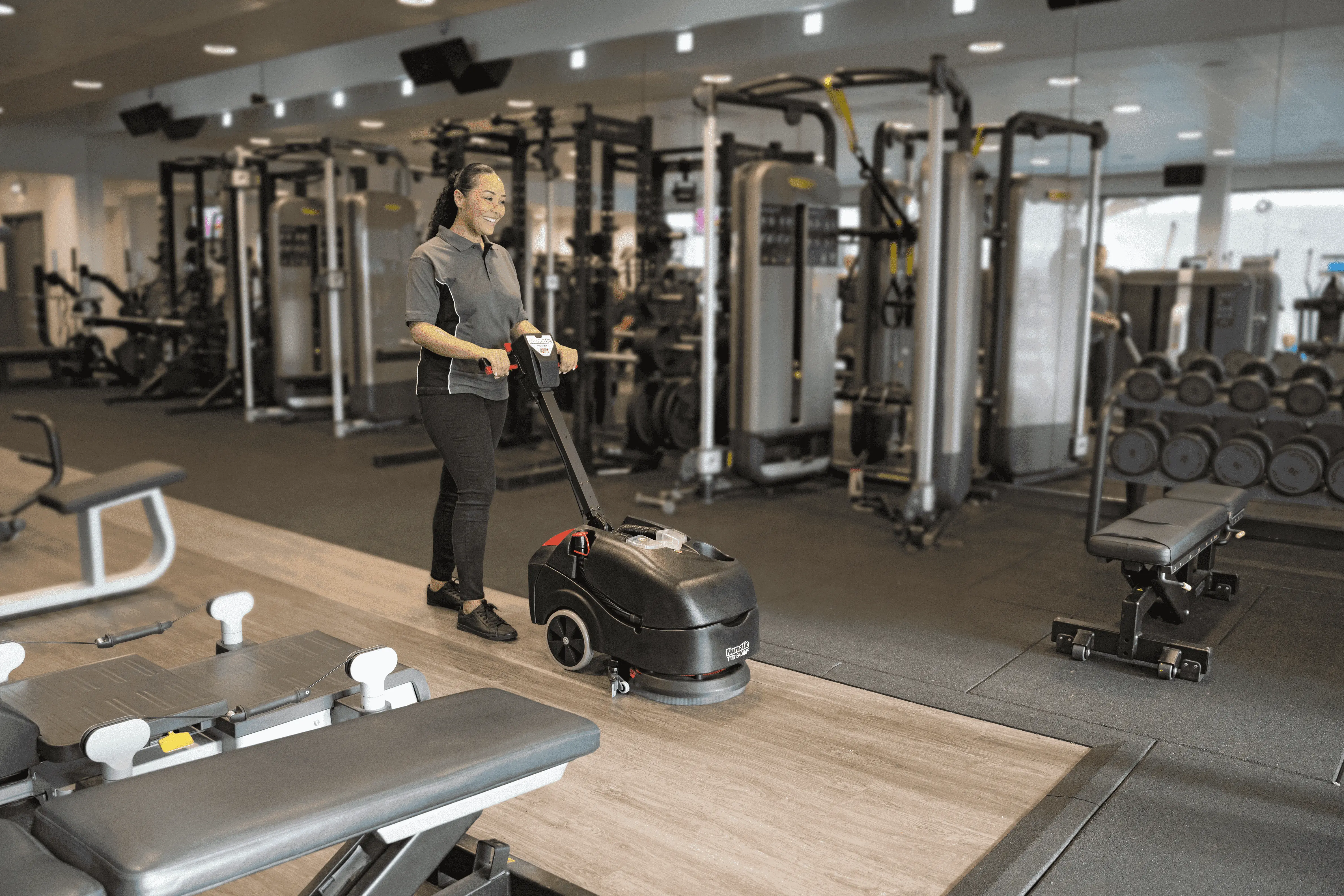 Scheuersaugmaschine mit schwarzem Gehäuse und Bürsteneinheit für die Bodenreinigung im Fitnessstudio